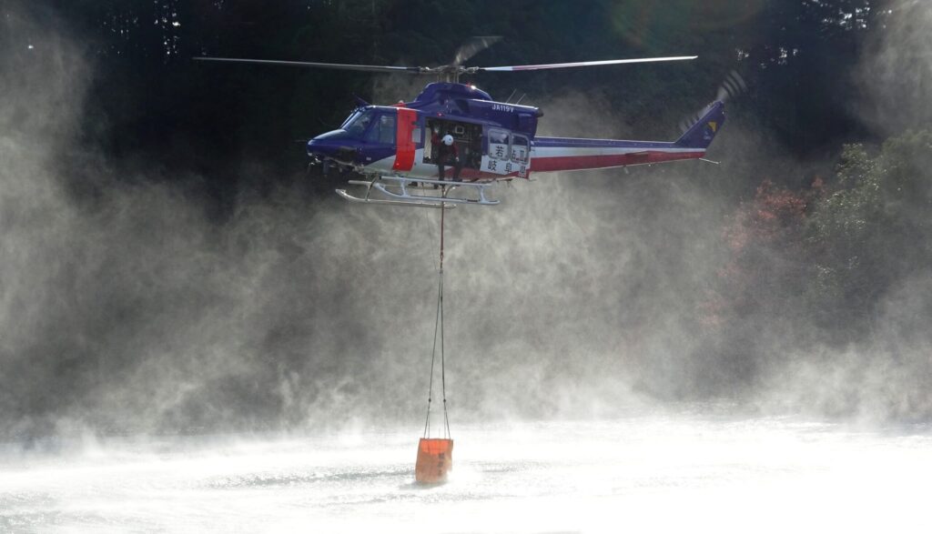 ため池で消火バケットに給水する消防防災ヘリ