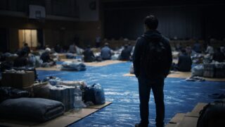 避難所で一人佇む男性